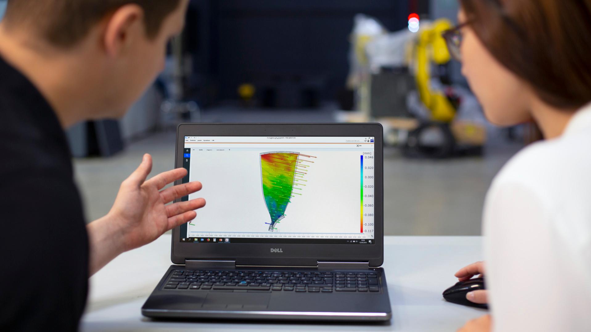 Two analysts look at the results of vibration analysis on a laptop.