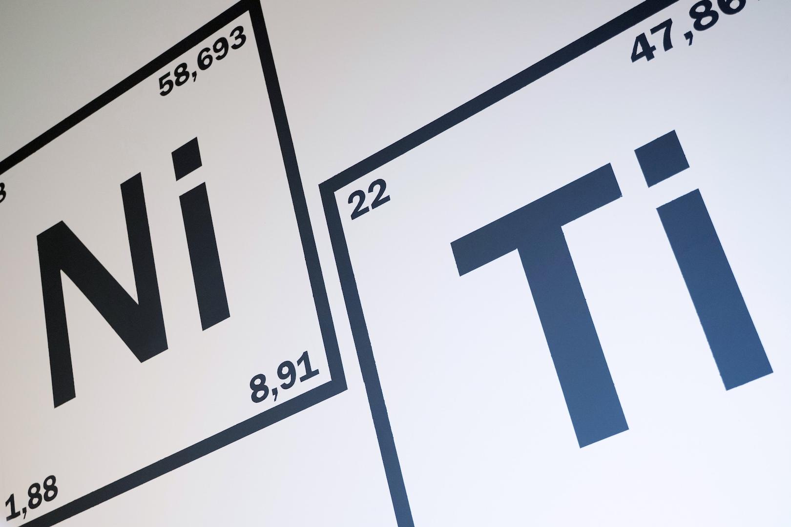 Wall graphic showing the chemical elements Nickel (Ni) and Titanium (Ti) represented as periodic table tiles.