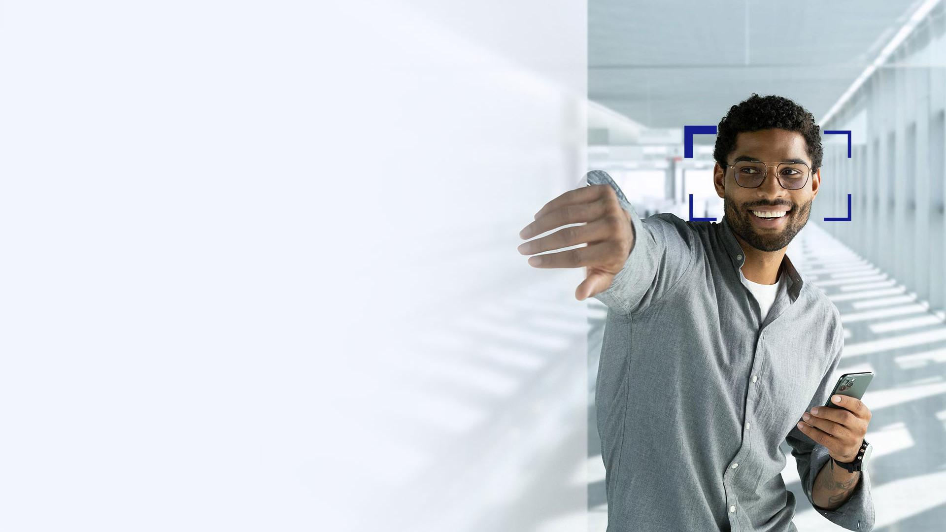 A young man with black hair smiling reaching with his hand through screen wearing ZEISS SmartLife lenses.