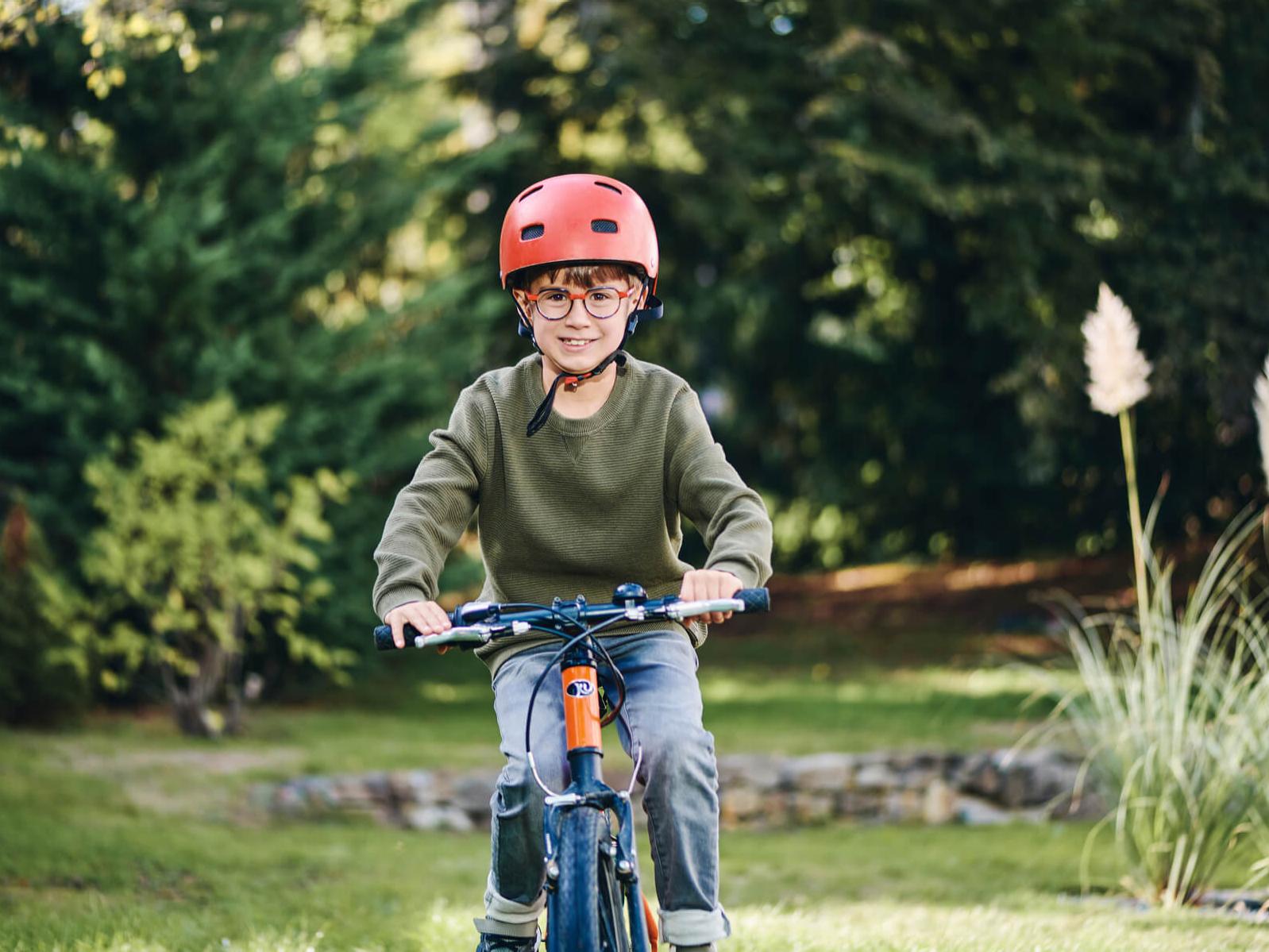 A young boy wearing ZEISS Myopia Management lenses on his bike outside.