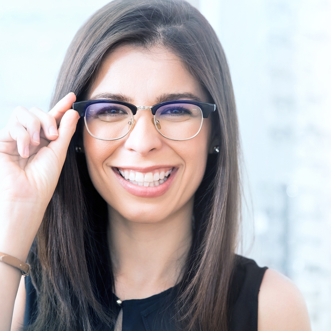 Portrait of beautiful young woman trying new glasses in optician store