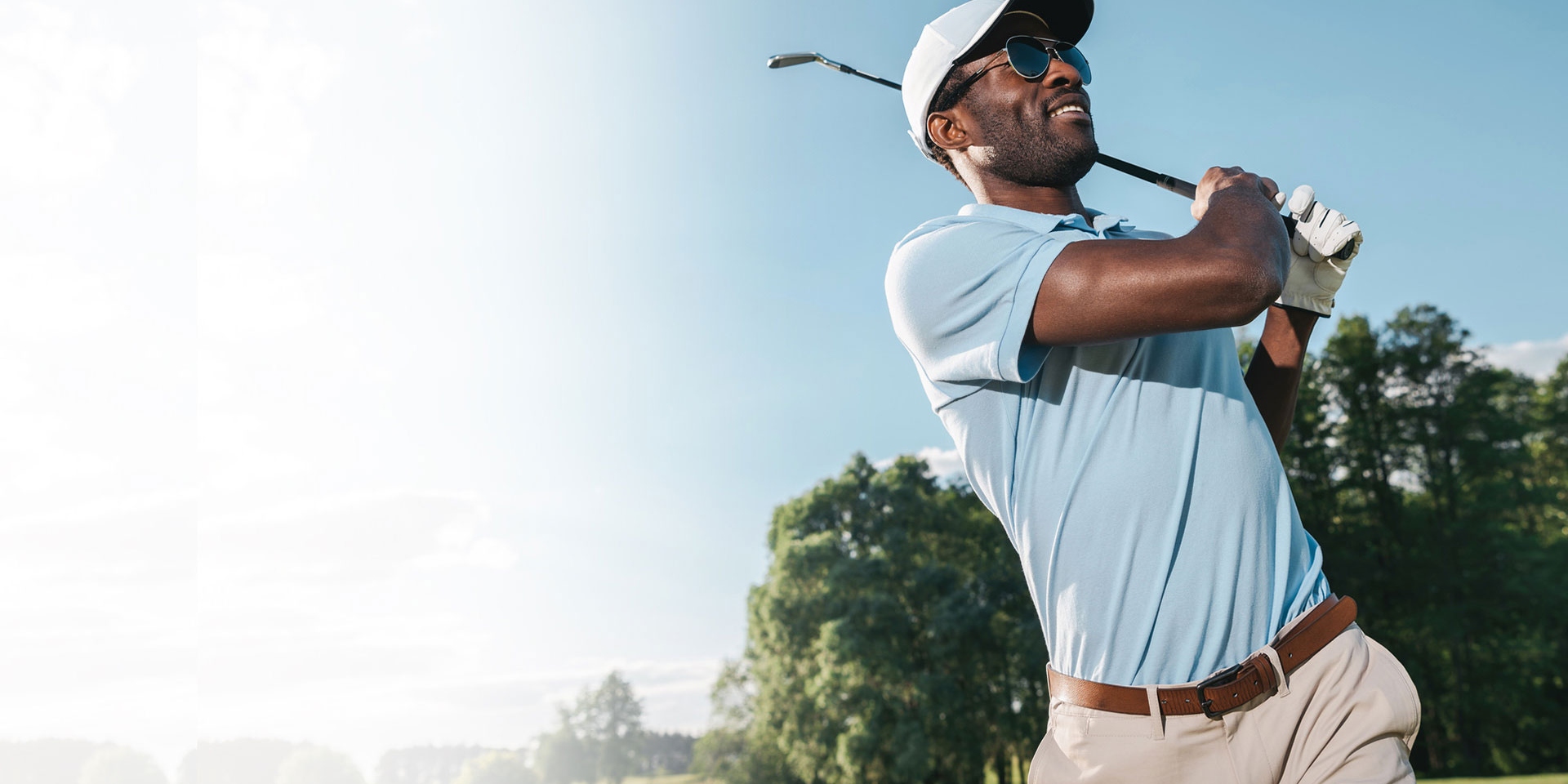Smiling african american man in cap and sunglasses playing golf