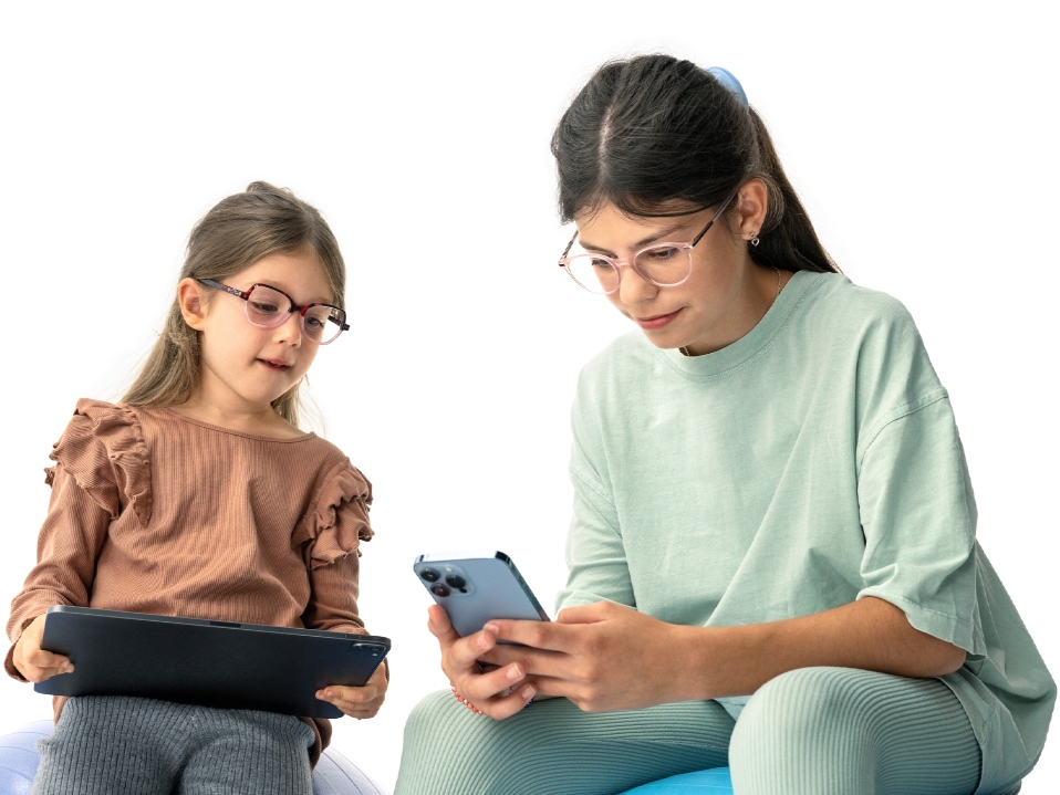 Two girls looking at digital devices at the suggested distance of more than 20cm.