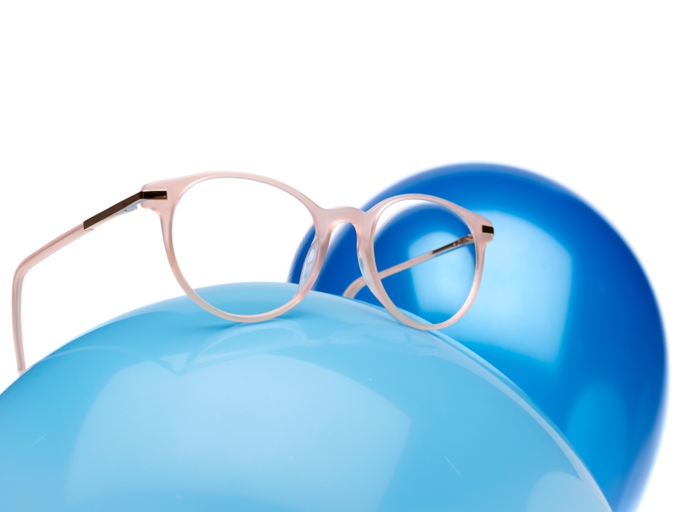Pink eyeglass frame with ZEISS MyoCare lenses on a blue balloon.